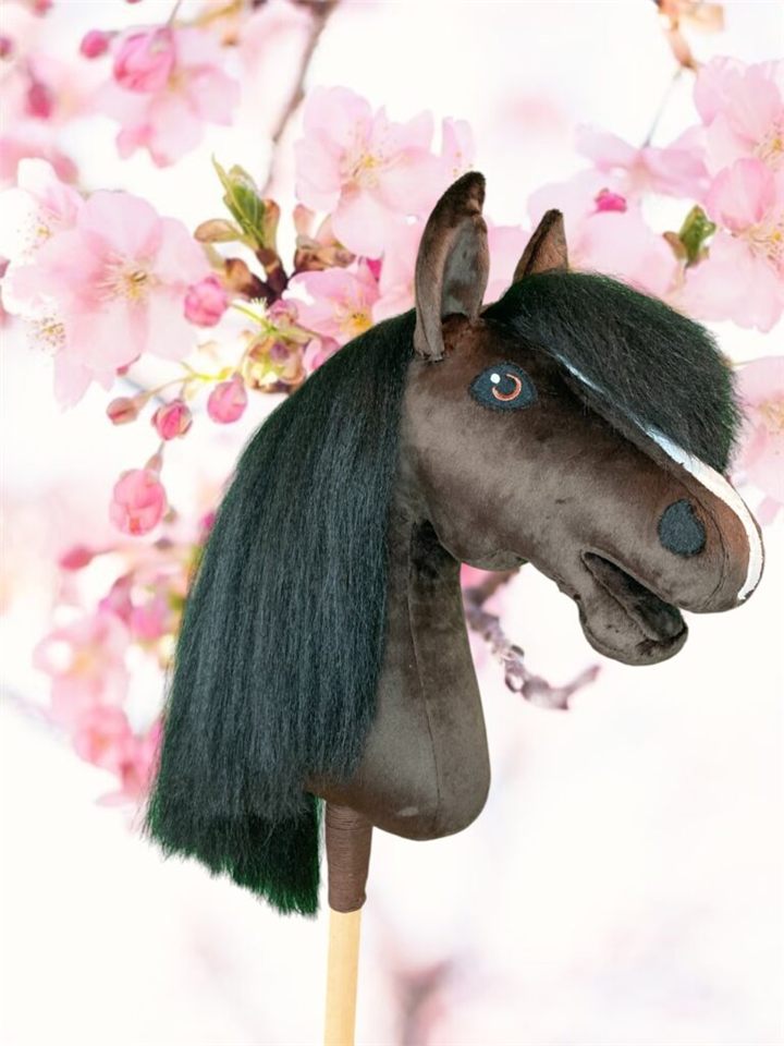 Donkerbruin hobby horse met grote bles voor roze bloesem